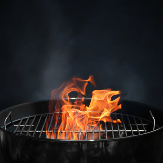 Flaming charcoal BBQ grill grate with open fire, ideal for outdoor family grilling in Winnipeg, Manitoba.