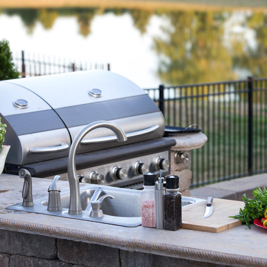 Built-in stainless steel BBQ grill and outdoor kitchen sink setup on a stone patio for a home in Winnipeg, Manitoba.