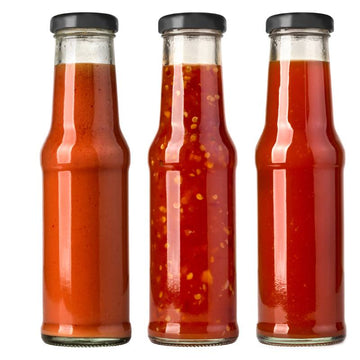 Three glass bottles filled with different regional BBQ sauces
